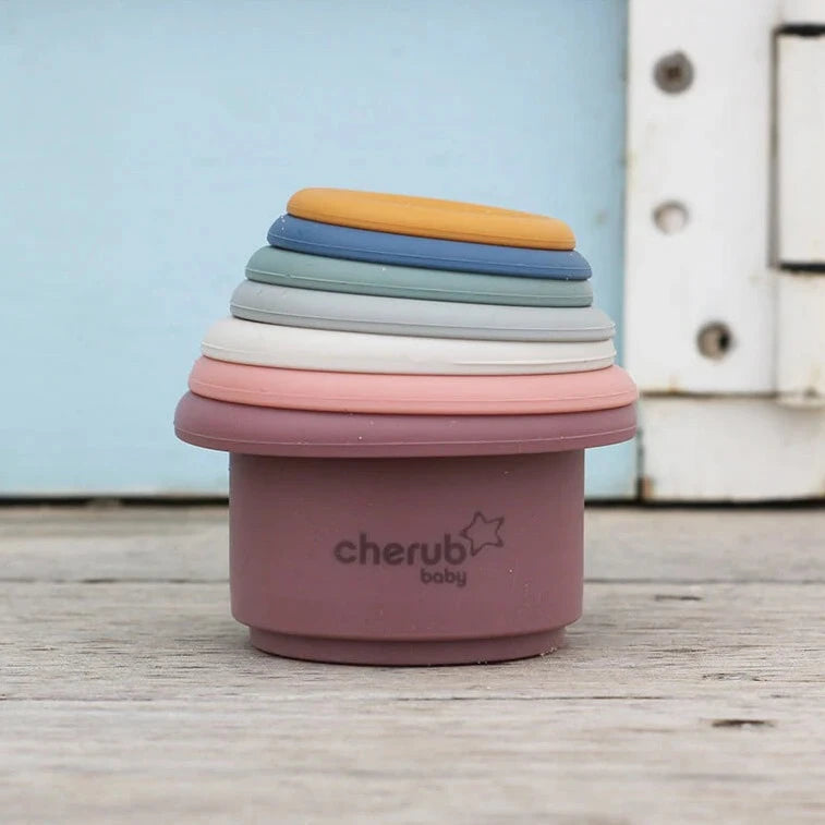 Child stacking Montessori style silicone stacking cups from Cherub Baby stacked up outside