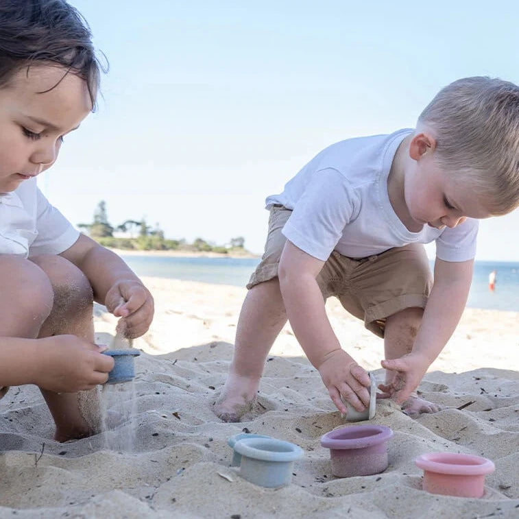 Children playing at the beach with Montessori style silicone stacking cups from Cherub Baby in ocean colour theme