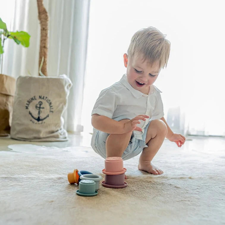 Child stacking Montessori style silicone stacking cups from Cherub Baby in sunlit room