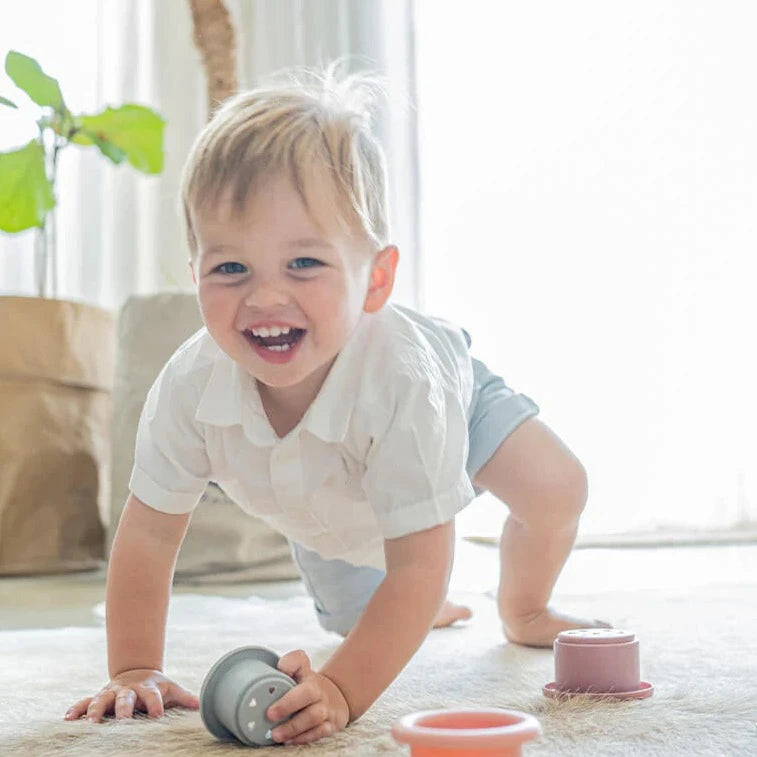 Child stacking Montessori style silicone stacking cups from Cherub Baby in sunlit room