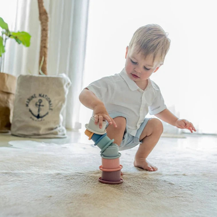 Child stacking Montessori style silicone stacking cups from Cherub Baby in sunlit room