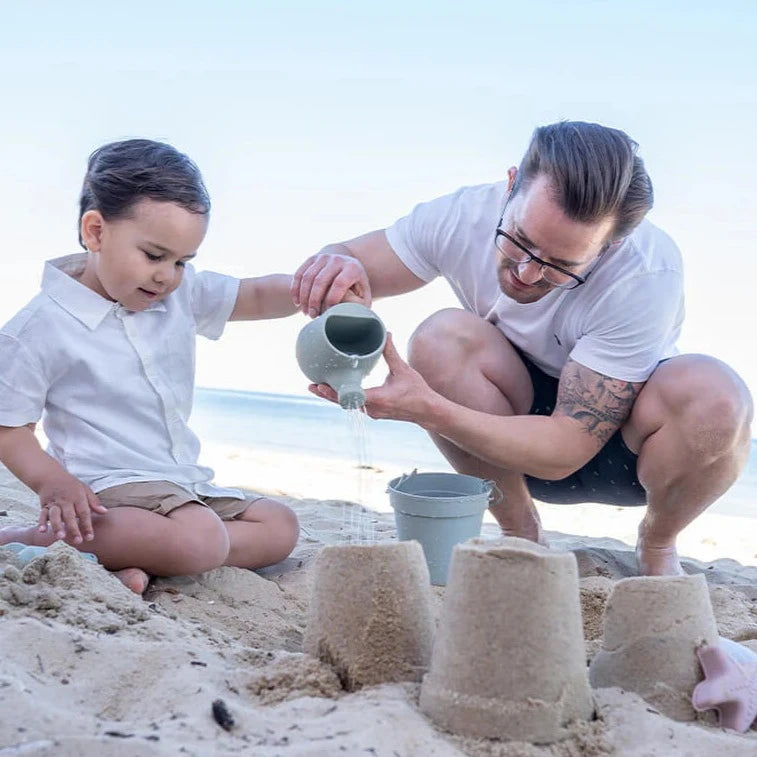 Dad and son playing with Cherub Baby - Bath & Beach Toys - Silicone Watering Can in Sage with water pouring out at beach