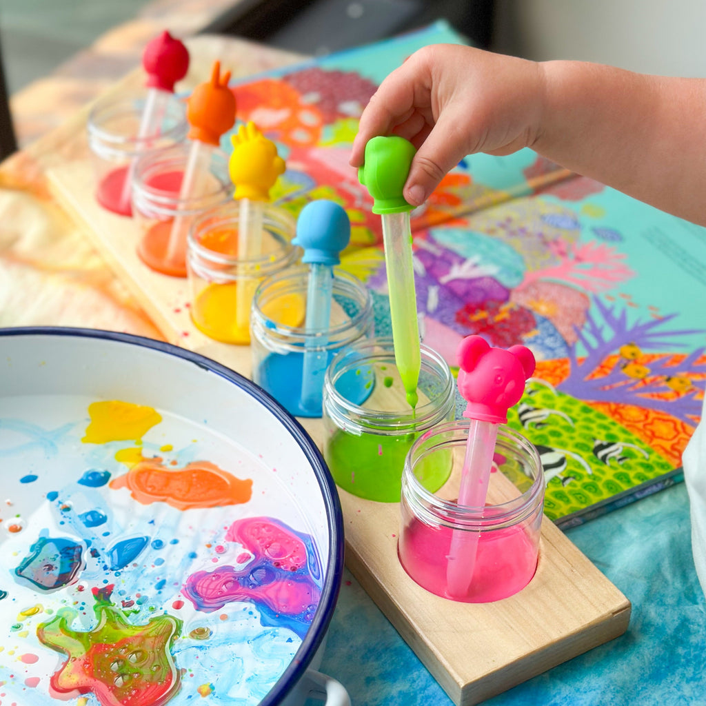 Child playing with animal drip droppers with different coloured paints and fish bookChild playing with animal drip droppers with different coloured paints and fish book