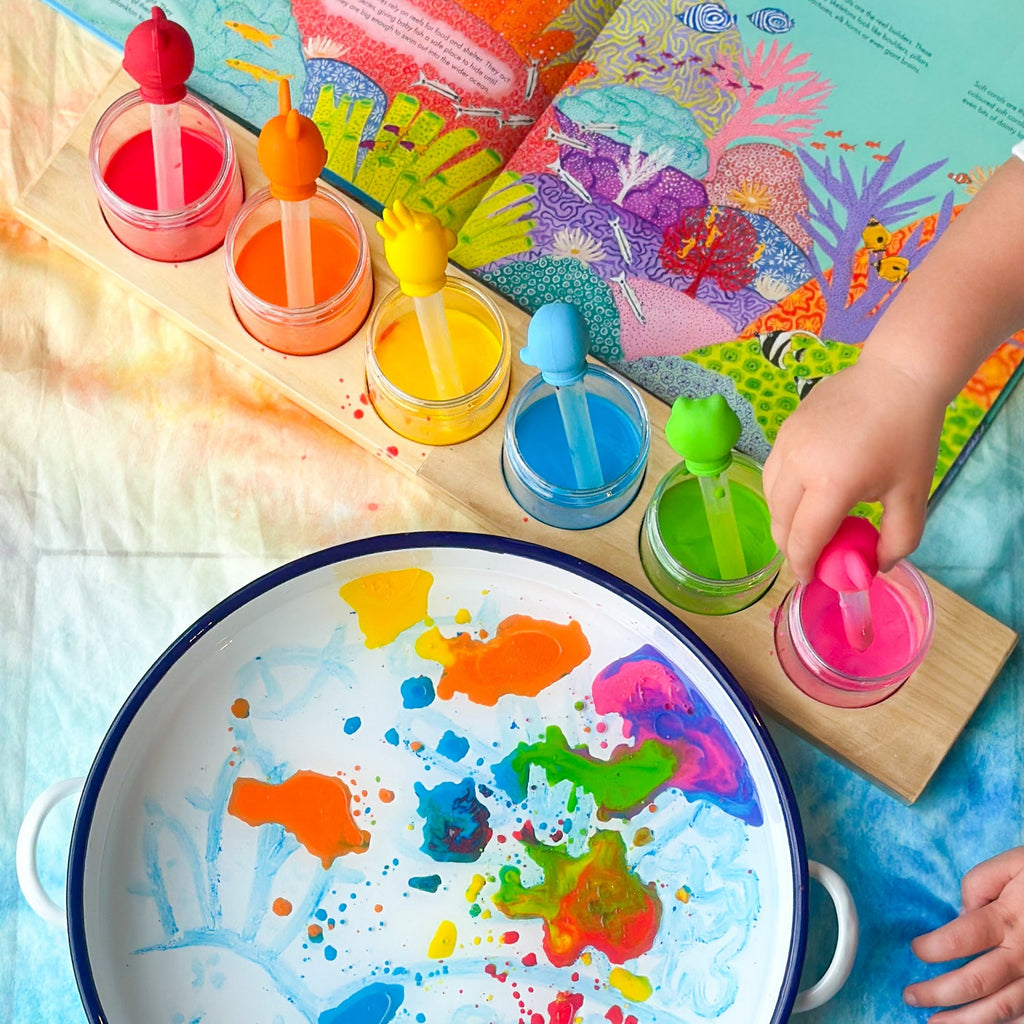 Child playing with animal drip droppers with different coloured paints and fish book