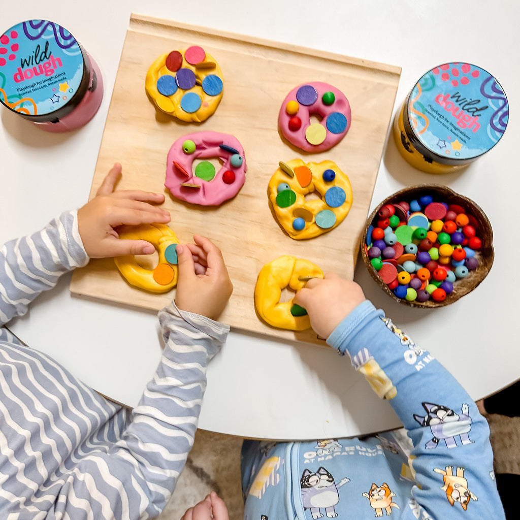 Children making Playdough donuts made from Wild Dough and colourful beads and loose parts