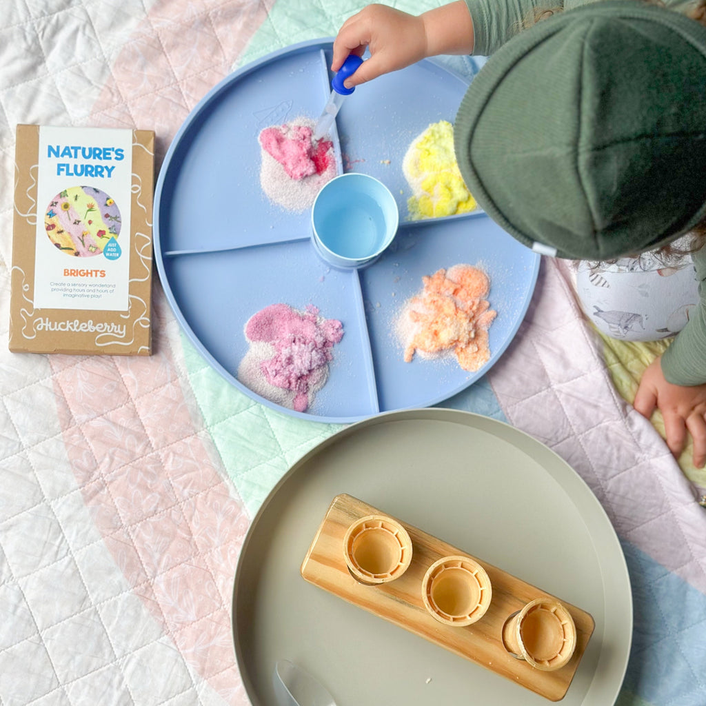 Child playing with natures flurry in the jellystone play tray set up  on a colourful play quilt