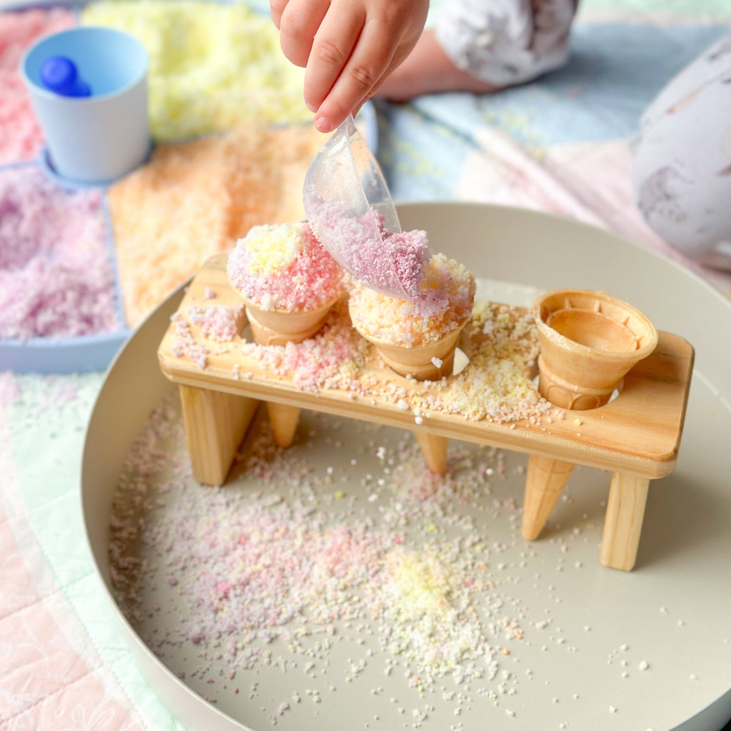 Child playing with natures flurry making icecream cones in the jellystone play tray set up  on a colourful play quilt