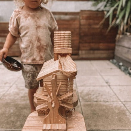 Explore-Nook-Eco-Hut-Water-Wheel played with a child with curly blonde hair